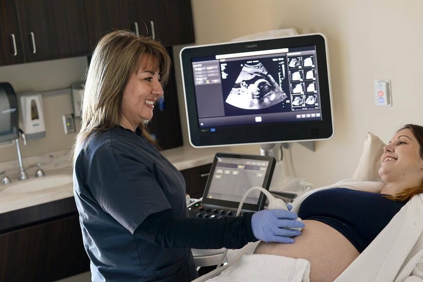 A sonographer performs a scan on a pregnant woman