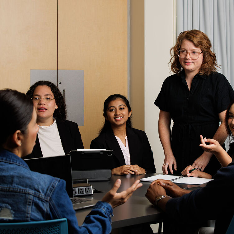 A teacher lectures to a small group of students in a conference room
