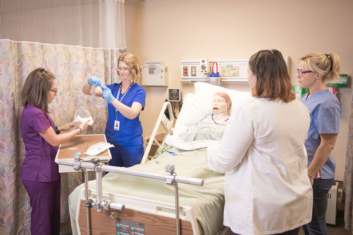 Nursing students practicing in the skills lab under the supervision of a faculty member