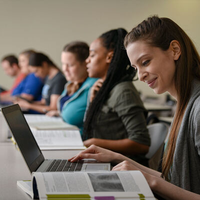 A female student works on her laptop in a classroom