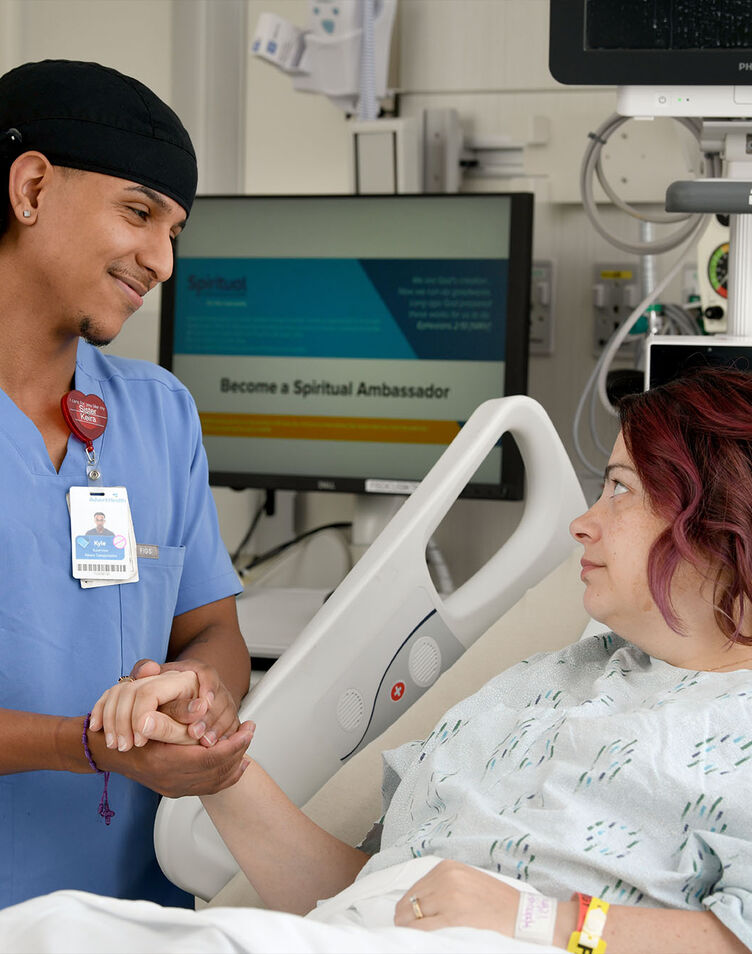 A nurse comforts a patient and holds their hand